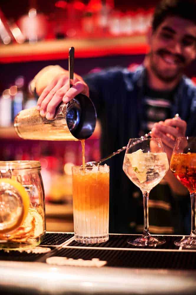 A man pours cocktails into a glass