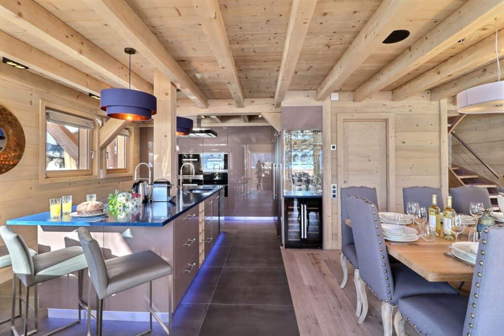 An open plan kitchen dining room in a wooden chalet, with exposed beams