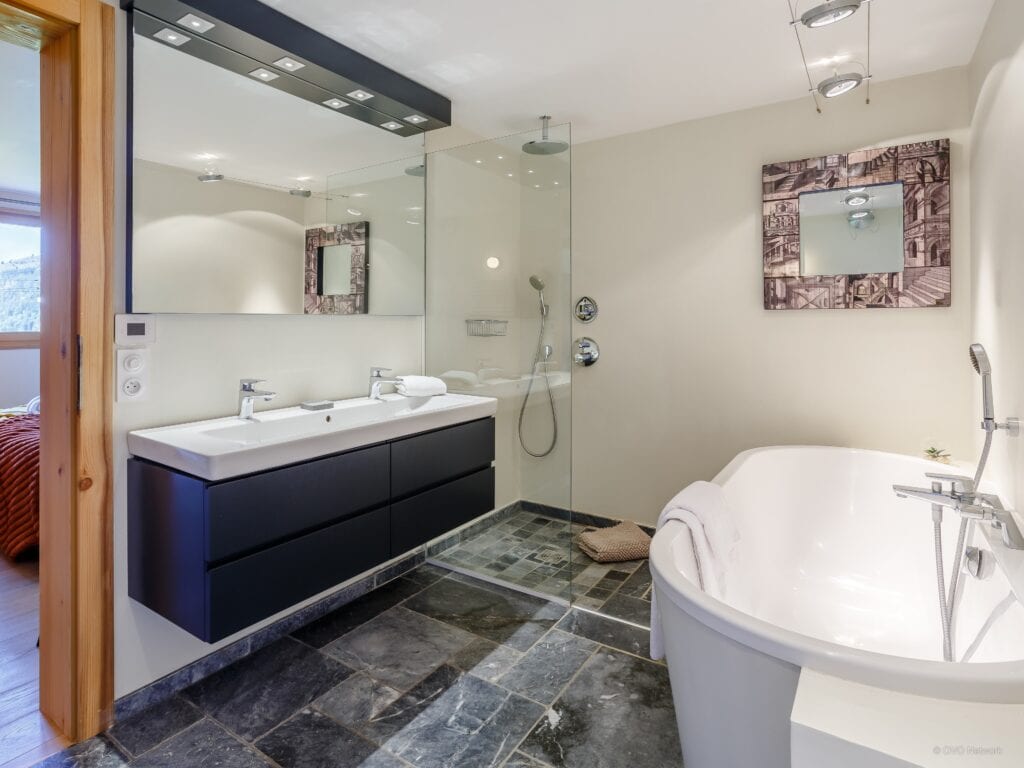 A bathroom with a white free-standing bath and large wash basin as well as a walk-in shower