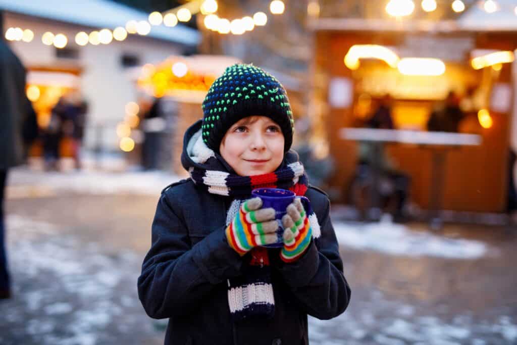 A young boy drinks hot chocolate at a Christmas market