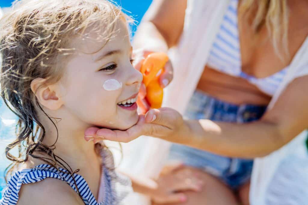 A mother applies sunscreen to a child's face