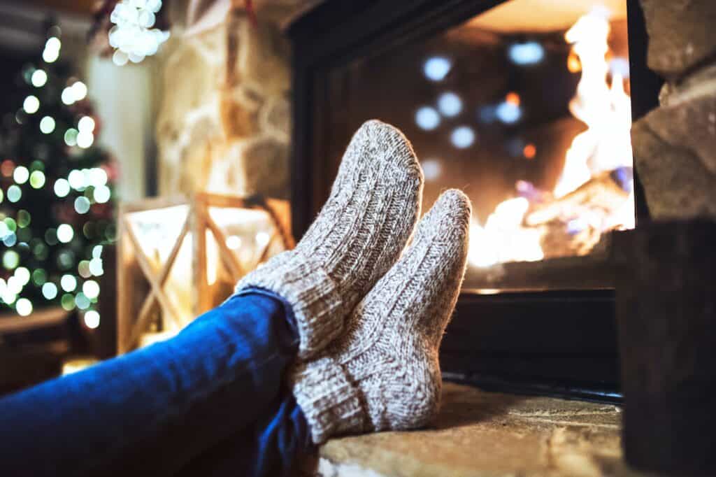 A pair of feet in cosy socks next to a fireplace