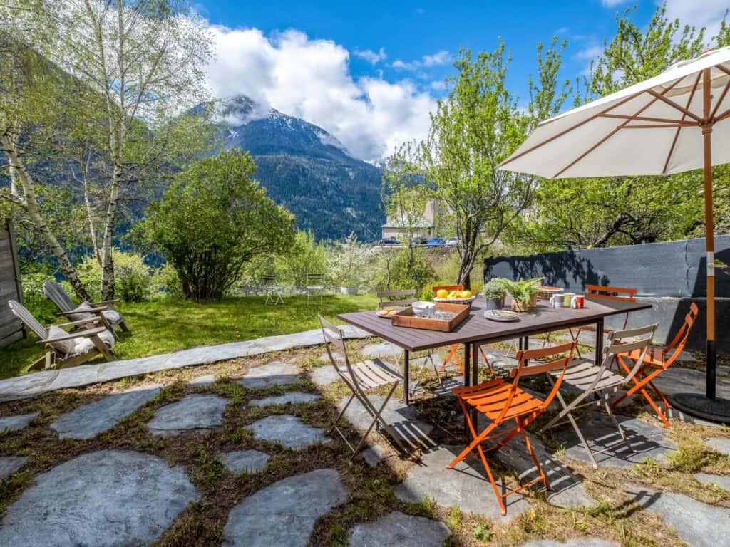 A table and chairs on a mossy terrace with a view of the mountains