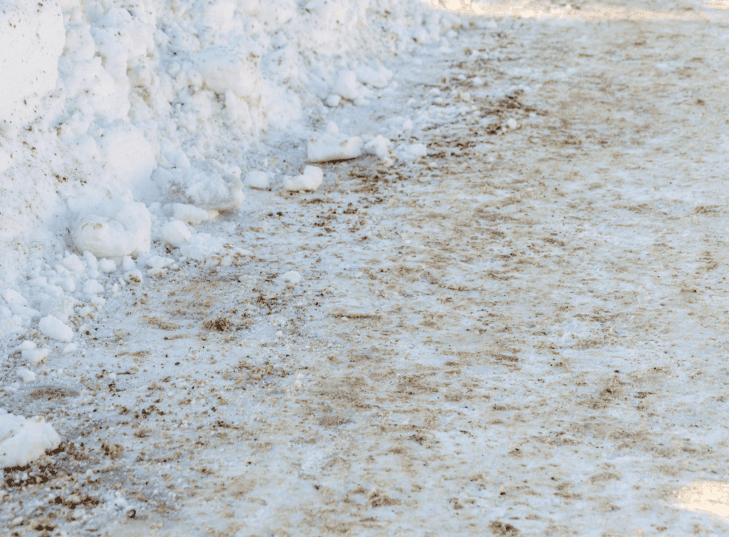 A snowy footpath covered with sand and salt