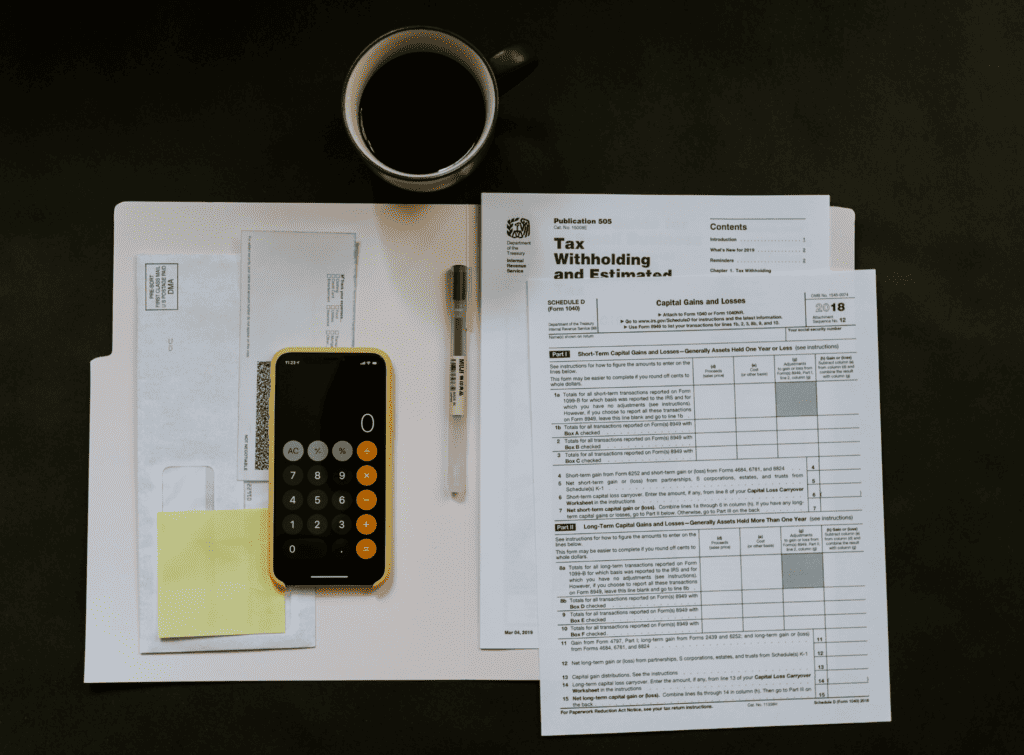 A file of documents open on a table with a calculator and a pen