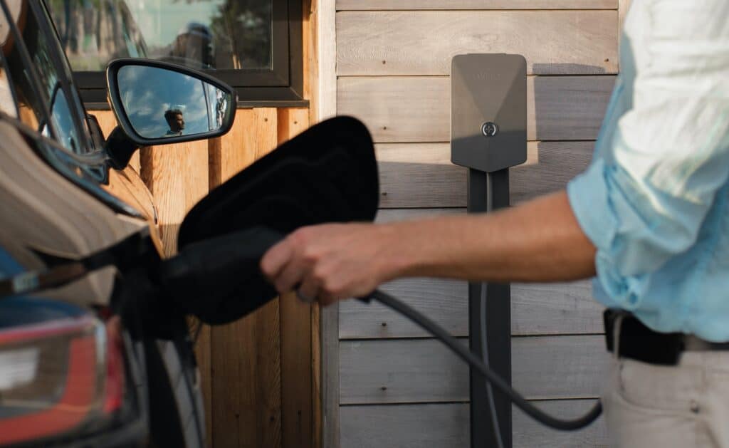 A man plugs in his car to a charging point
