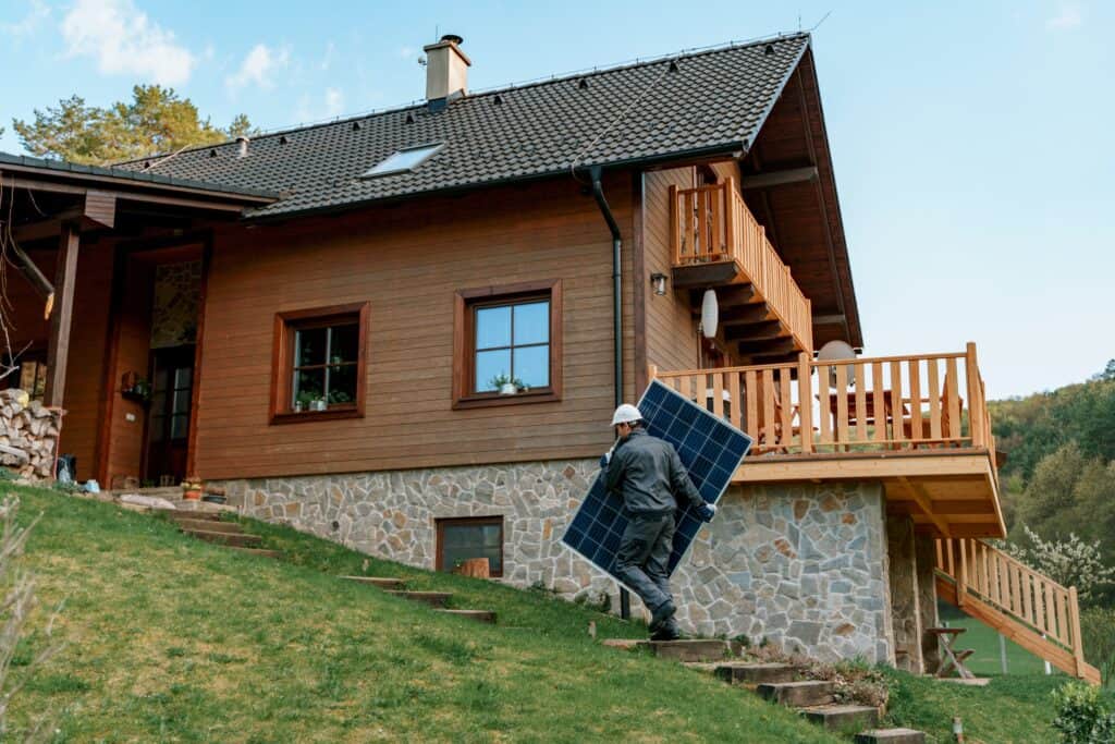 A man carries a solar panel outside a chalet