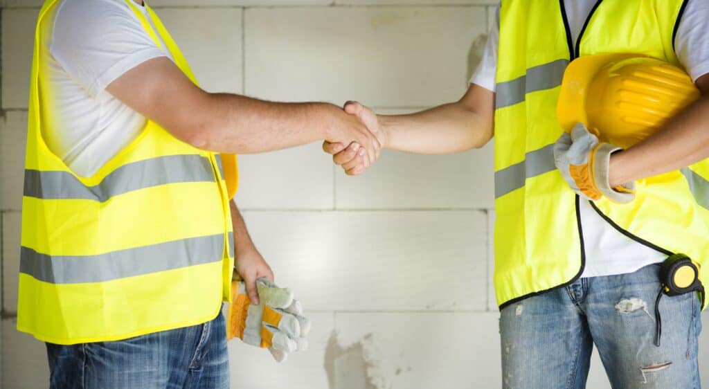 Two people wearing high visibility jackets shake hands