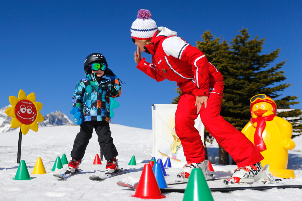 Monitrice de l'ESF donnant un cours de ski à un enfant. 