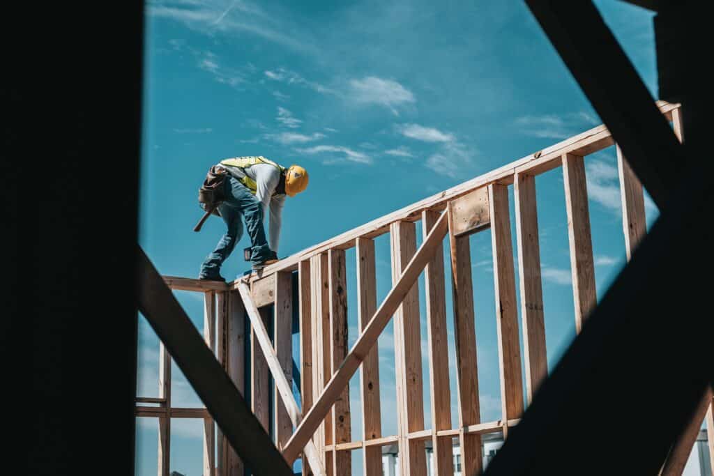 A builder stands on framework with a drill