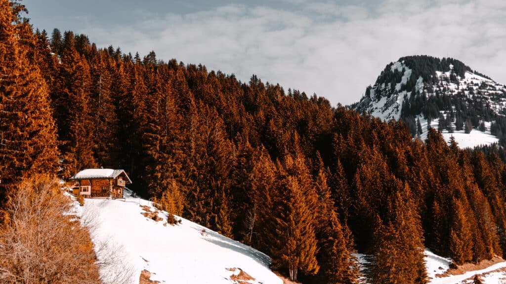 A chalet stands on a mountain in snow in autumn