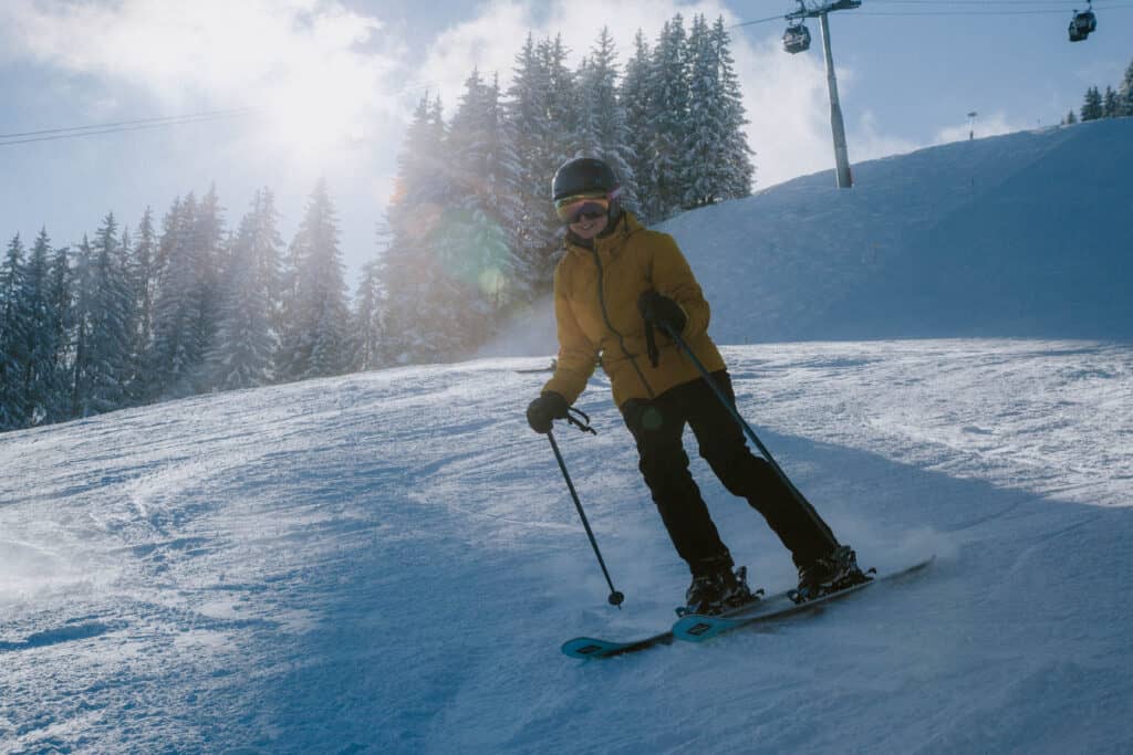 A person in a yellow jacket skis down a slope