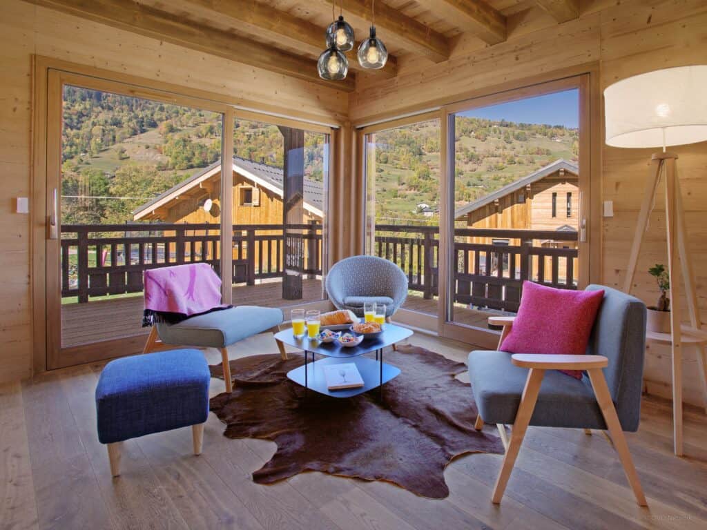 Salon boisé avec fauteuils et baies vitrées donnant sur les montagnes.