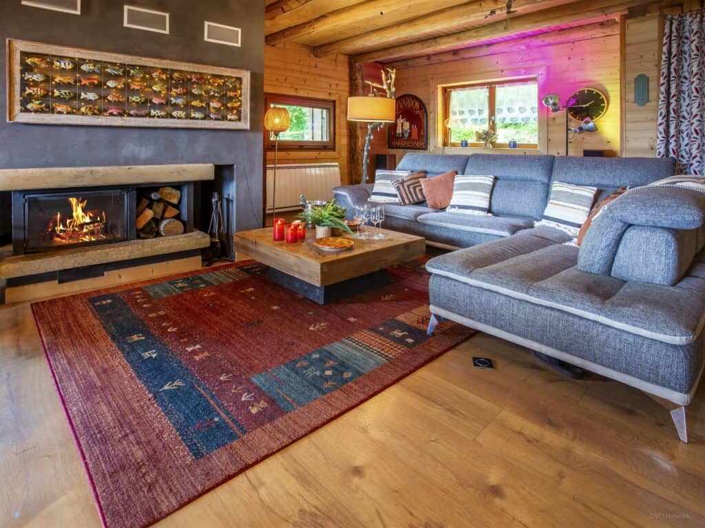 Spacieux salon pour 10 dans un chalet des Alpes, avec canapé et cheminée.
