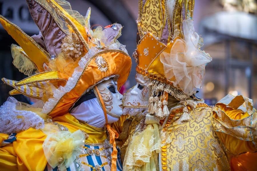 Two people wearing masks and extravagant costumes at Annecy's Venetian Festival