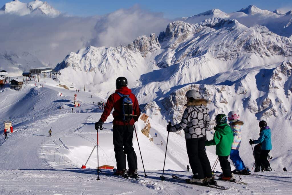 Une famille de skieurs en haut d'une piste en décembre.