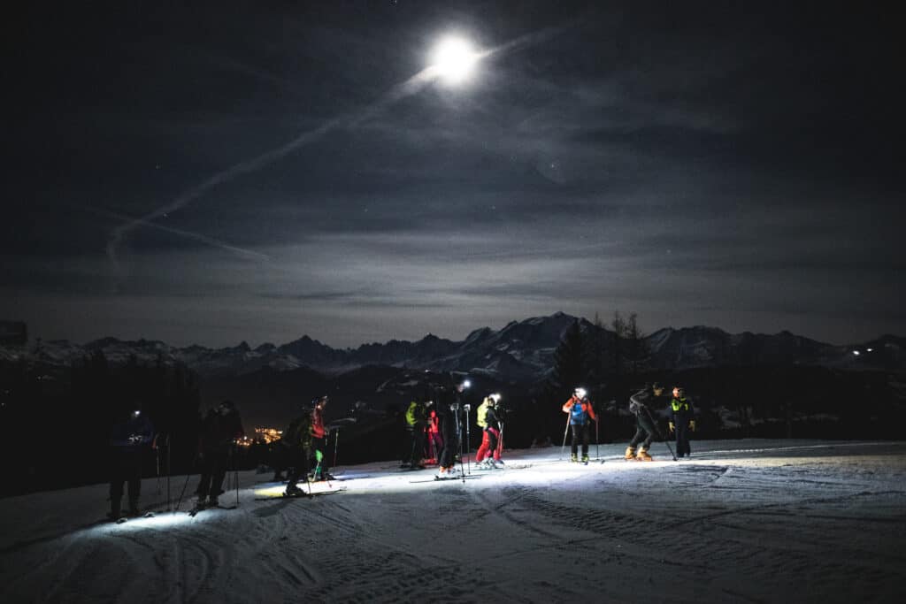 A group of people ski touring at night