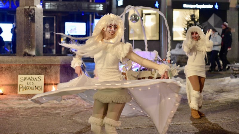 Two women in circus outfits dance in the street