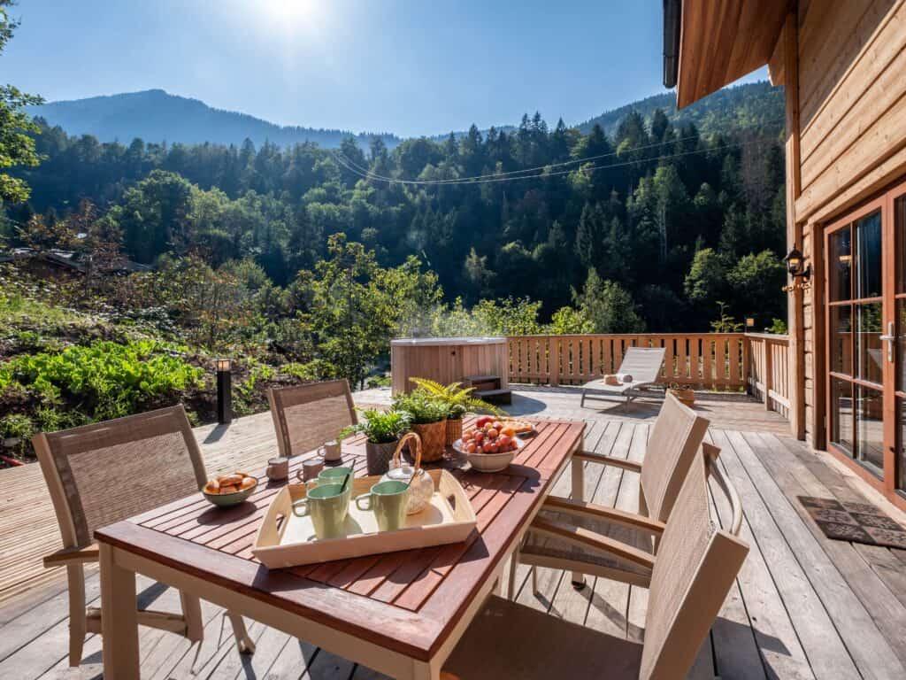 The terrace at Chalet Choquette, with a table and chairs, a sunbed and a hot tub
