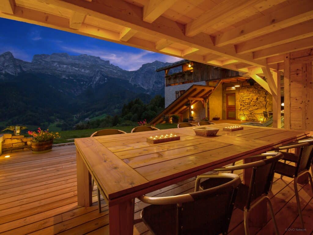 A partially covered terrace with a view of the mountains at night