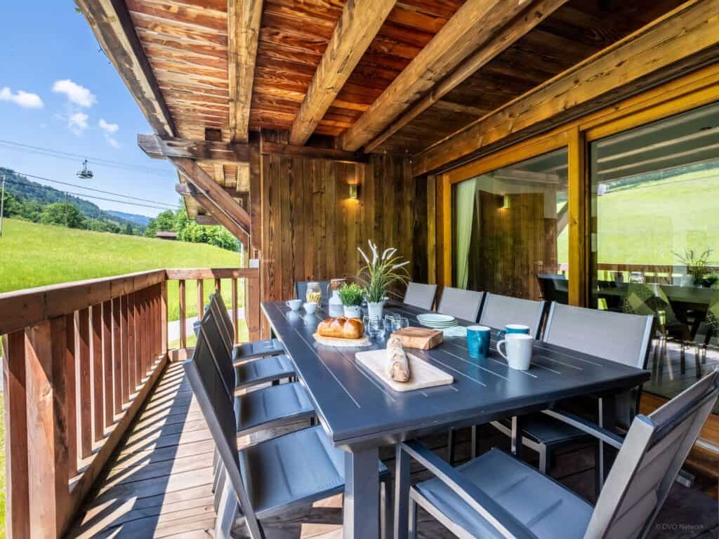 A dining table and chairs on a balcony overlooking pastures