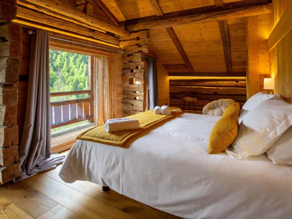A bedroom in a wooden chalet with doors on to a balcony