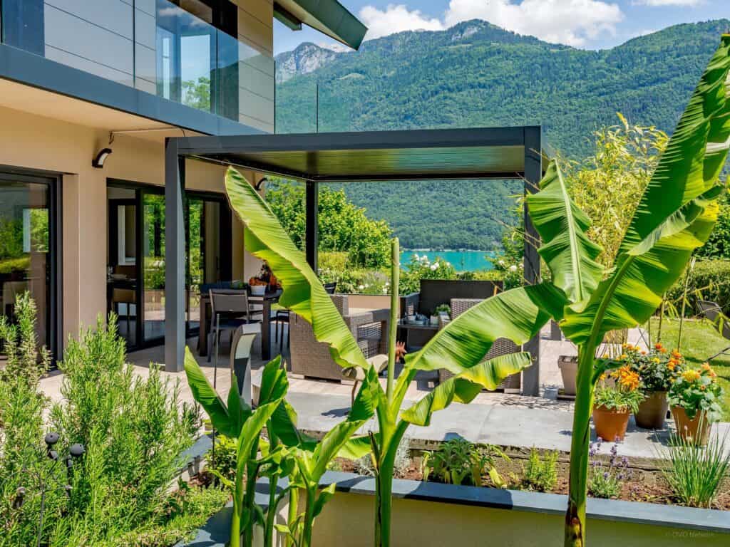 Jardin avec pergola et vue sur un lac.