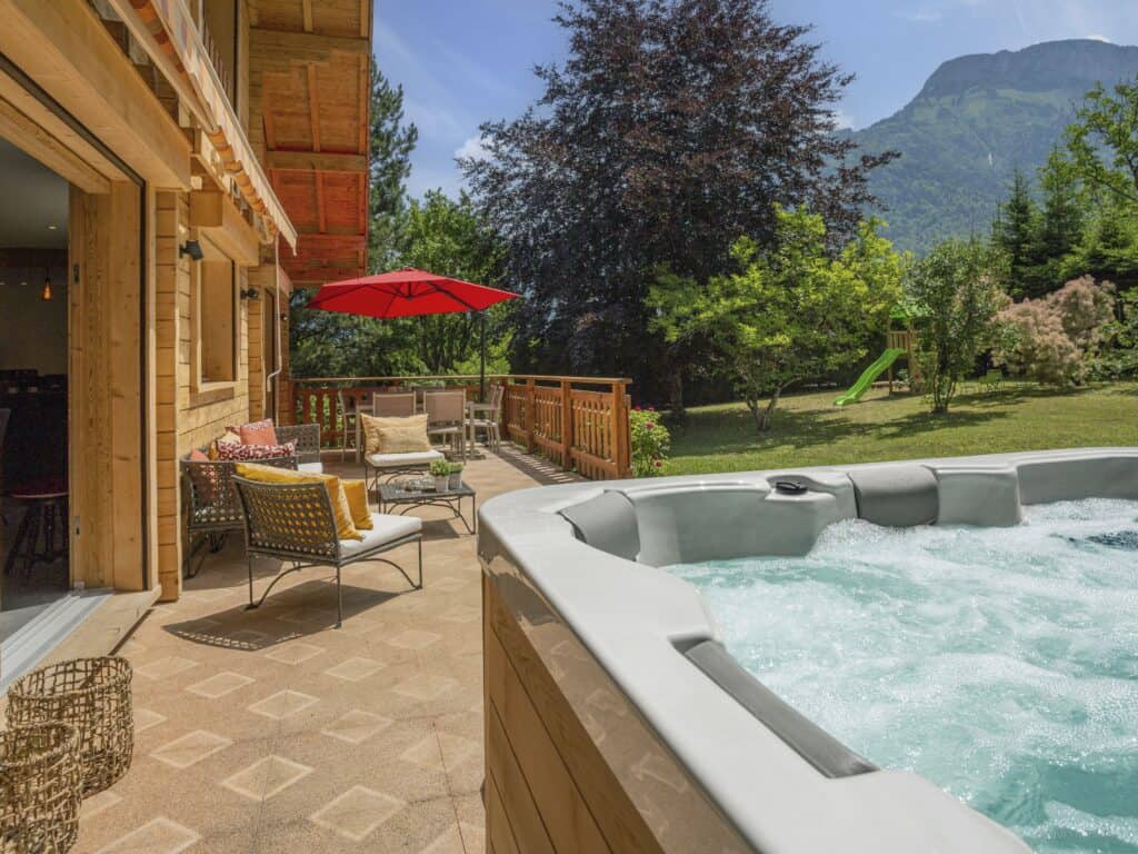 A hot tub and lounge furniture on a terrace in the garden of a chalet