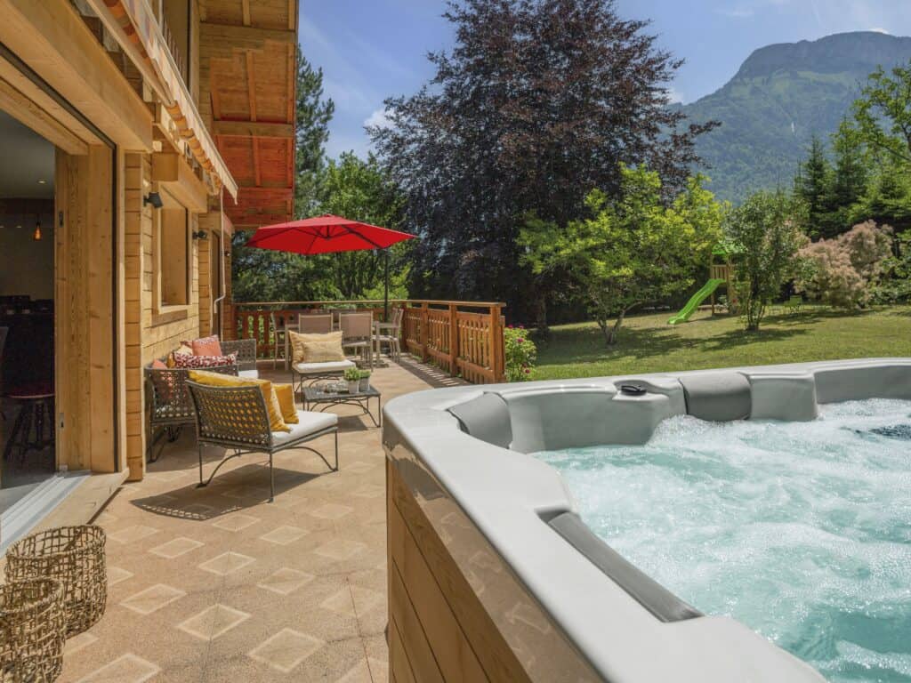 Jacuzzi sur une terrasse avec salon de jardin.