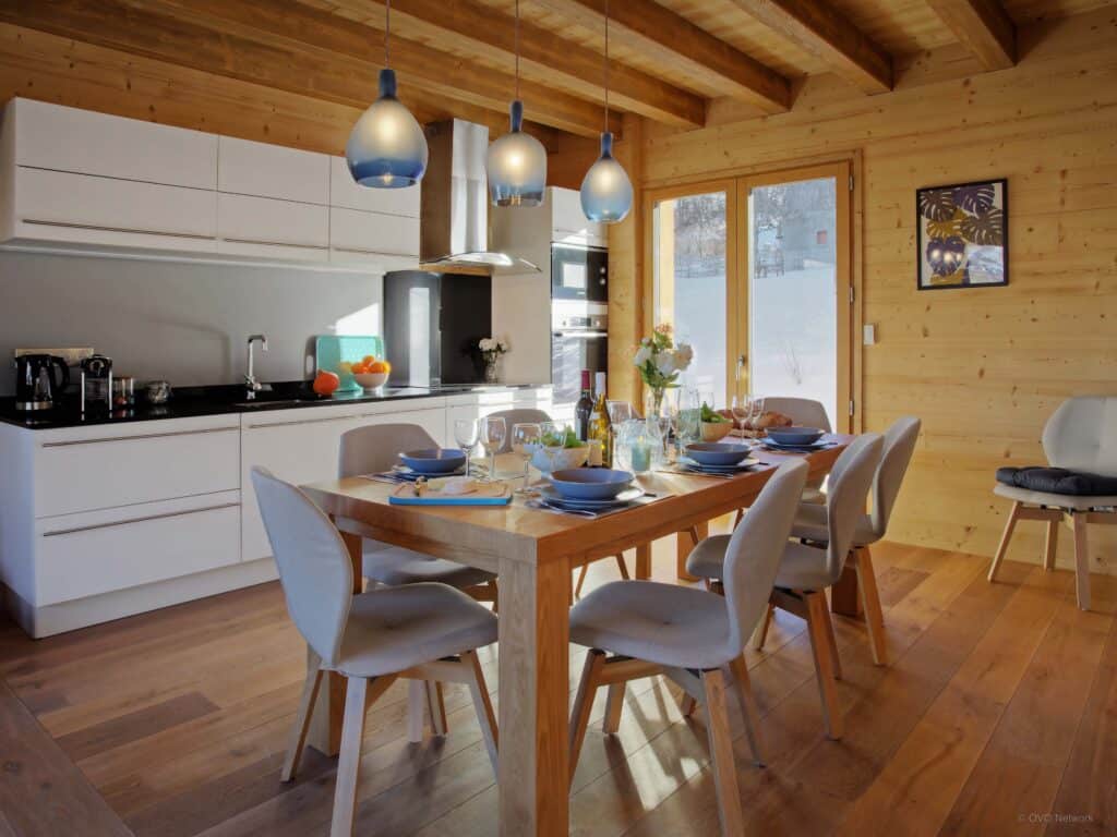 An open-plan kitchen and dining table  with doors opening to a snowy garden