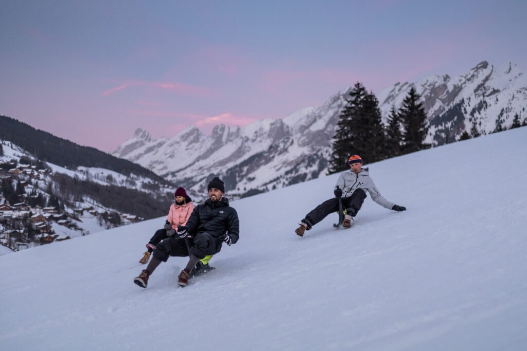 3 people paret sledging down a ski slope