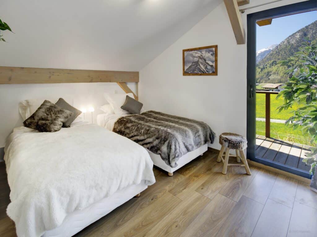 A twin bedroomm with access to a terrace with mountain views