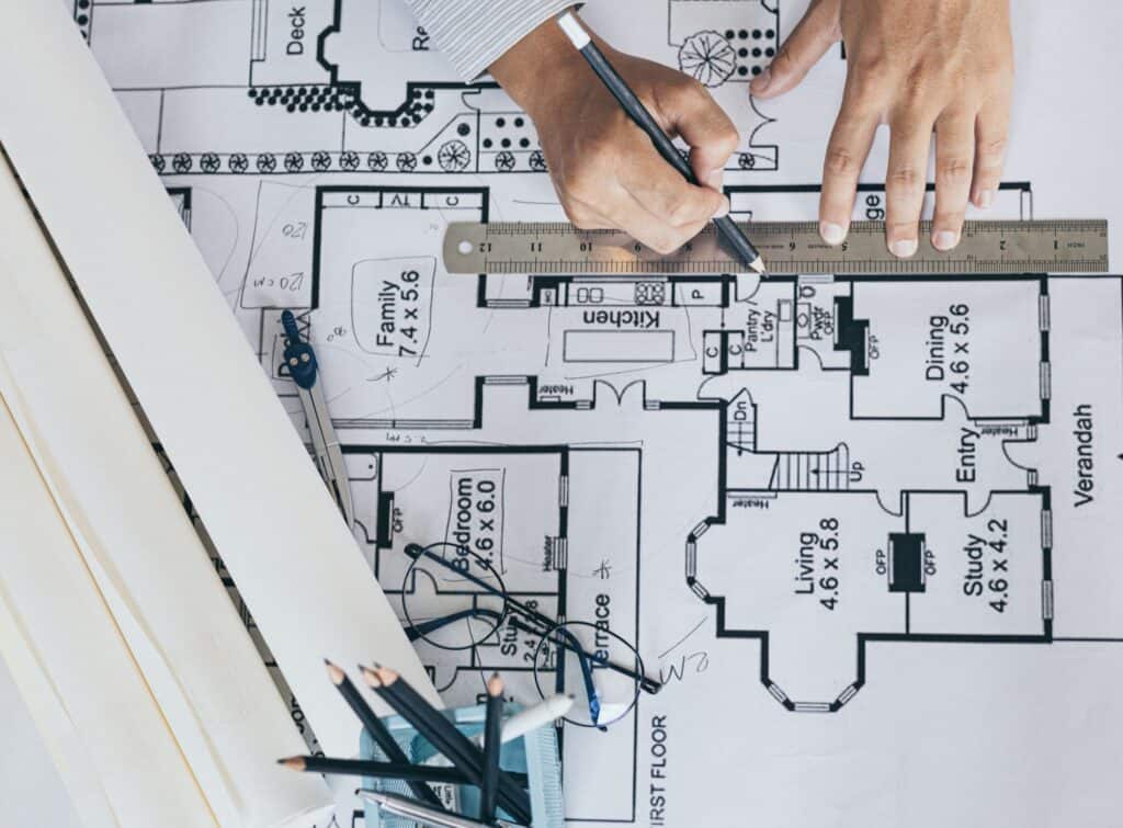 Mains traçant au crayon sur un plan 2D.