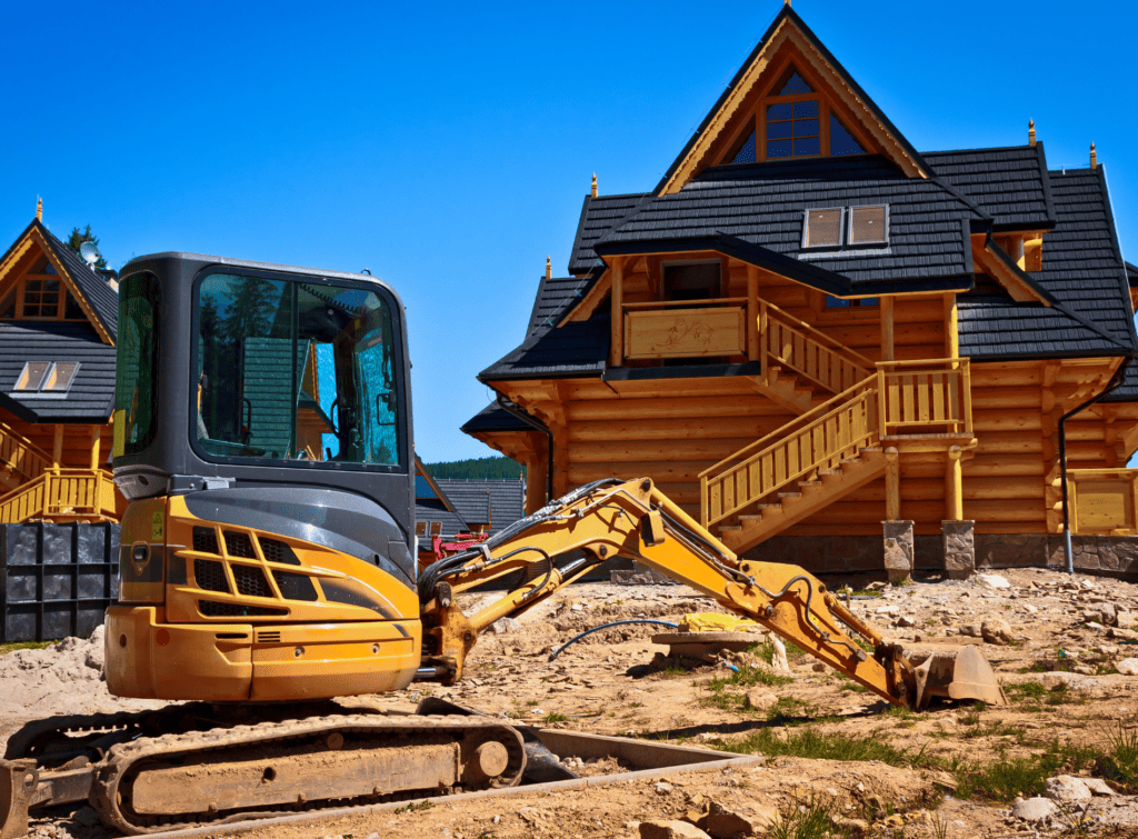 Pelleteuse jaune devant chalet en construction.