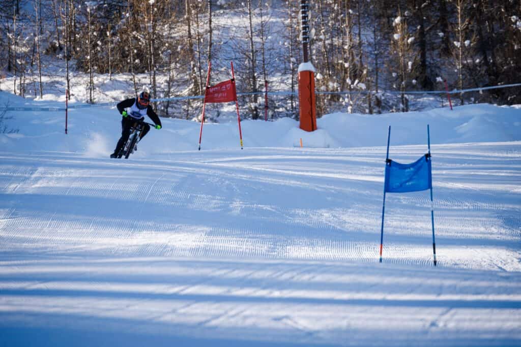A person rides a bike down a ski slope