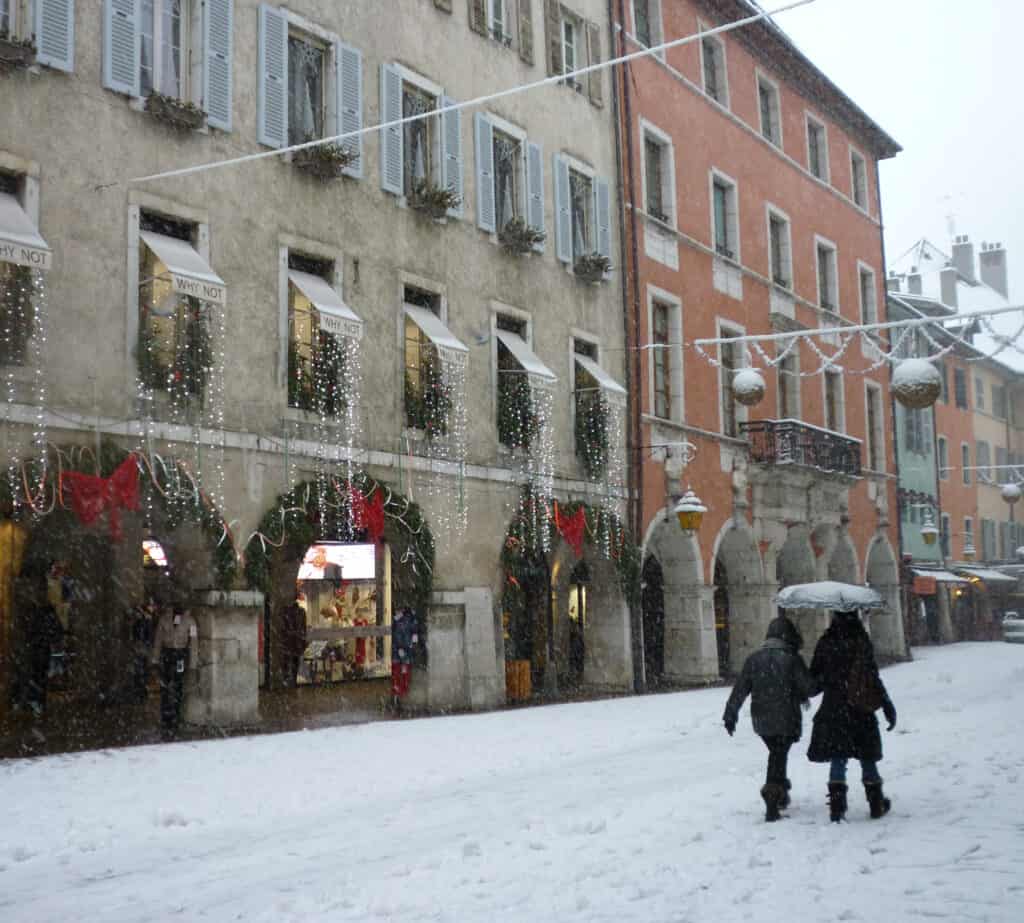 Deux personnes marchent dans une rue enneigée d'Annecy
