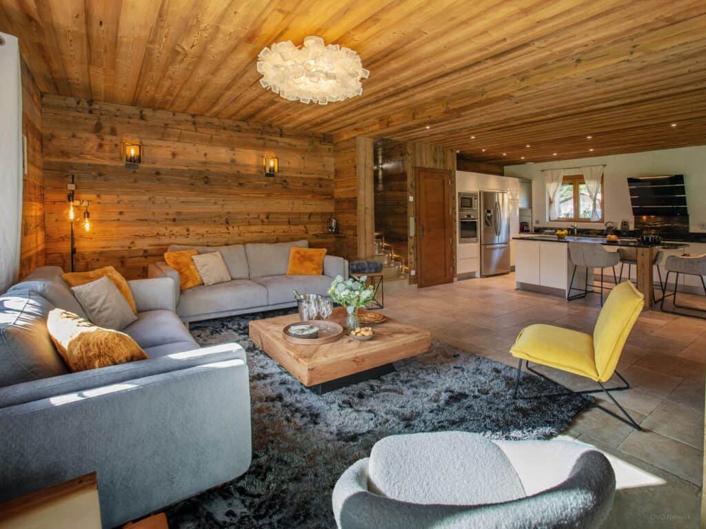Pièce spacieuse avec deux grands canapés, tapis douillet, et une cuisine ouverte en arrière-plan.