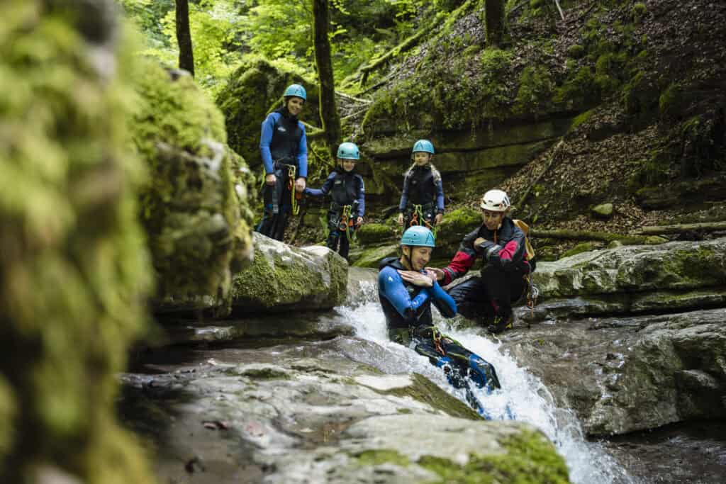 Family doing canyoning surrounded by woods.