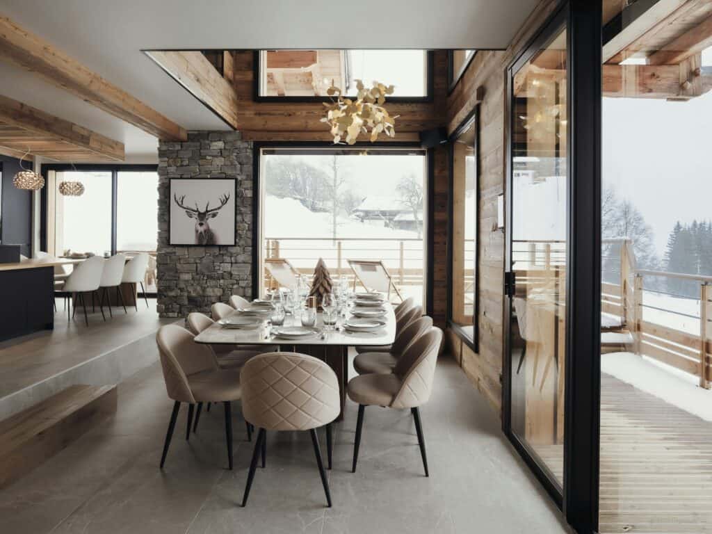 Dining table surrounded by bay windows and a snowy landscape.