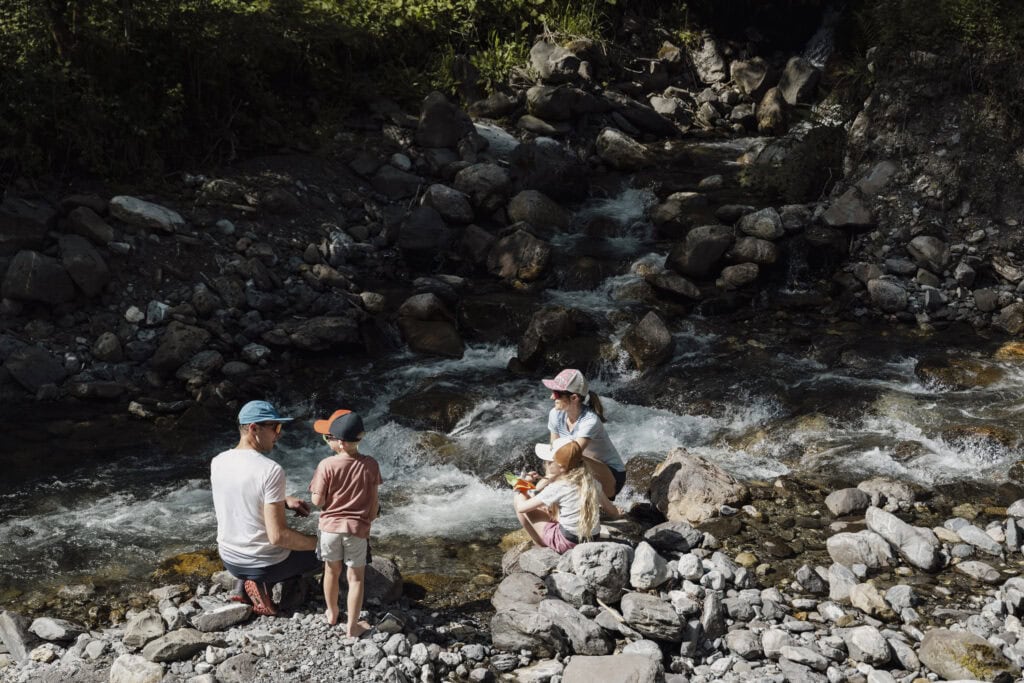 Family sitting by a mountain river in the summer.