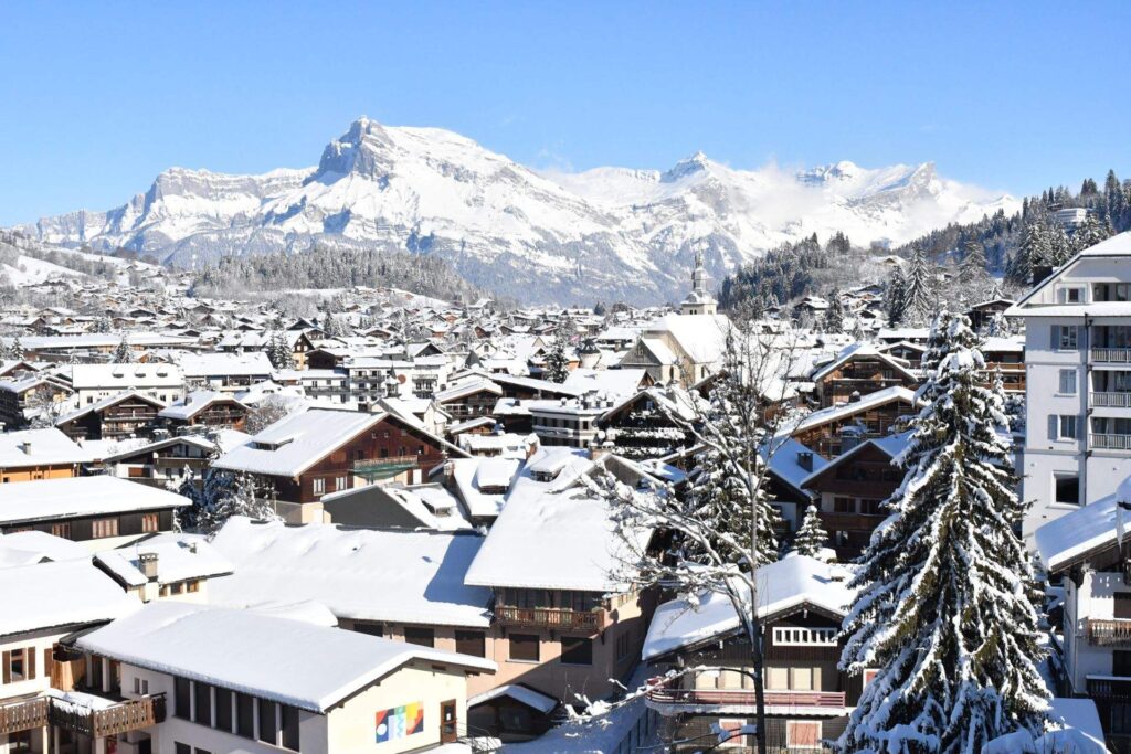 The village of Megève under the snow, with mountains in the background.