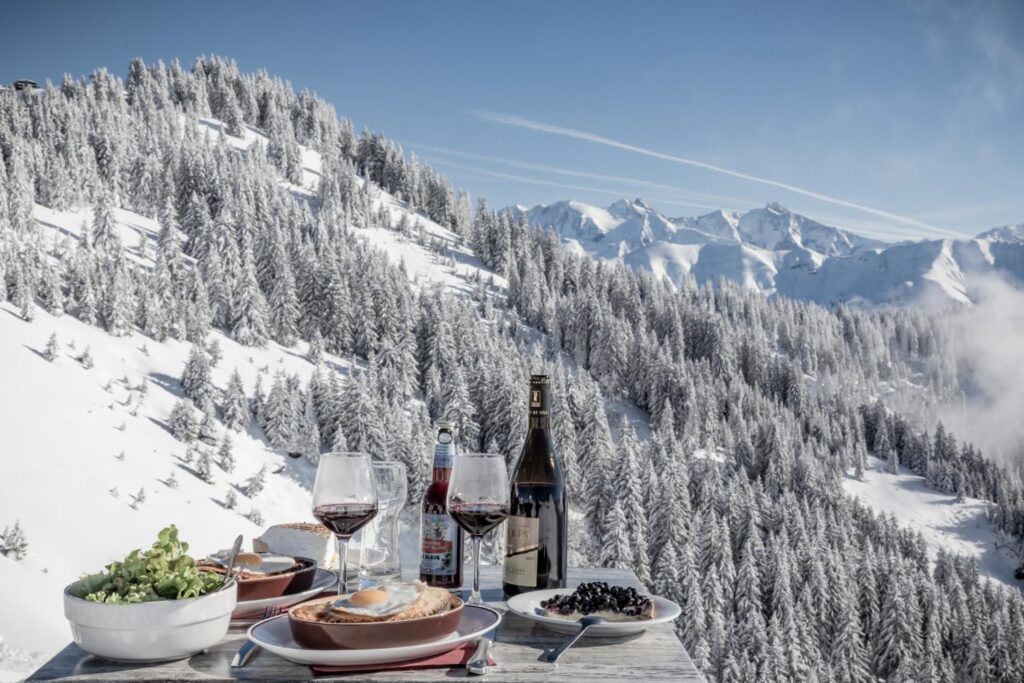 Plateau de produits savoyards avec une forêt enneigée en arrière-plan.